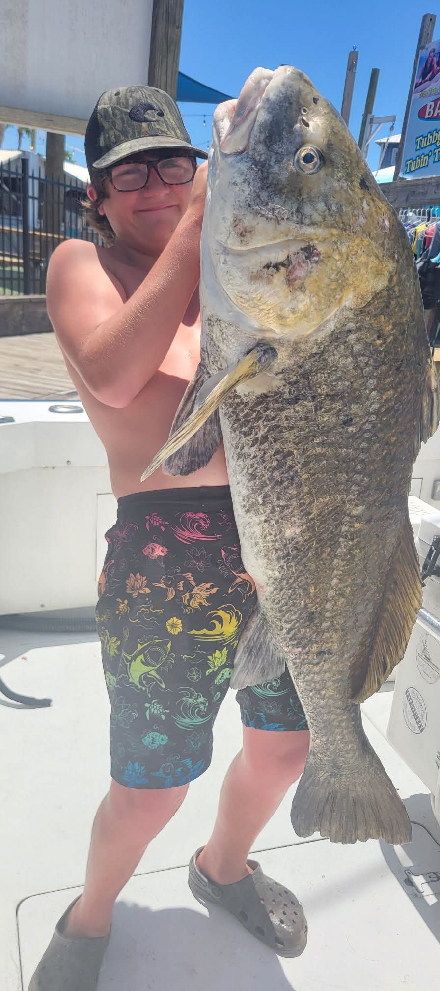 Young angler holding a huge grouper at the dock